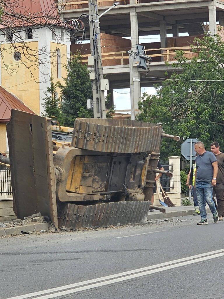 Buldozer căzut din trailer, lângă o stație de autobuz din Sânmartin. Primarul: „Putea să se întâmple o tragedie”